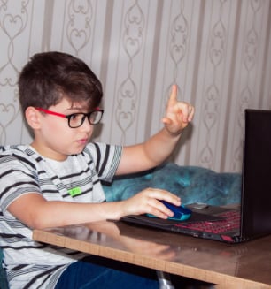 Young boy using mouse while looking at computer