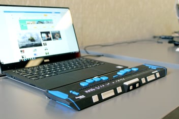 Laptop with refreshable braille display sits open on a desk. [Image credit: Elizabeth Woolner]