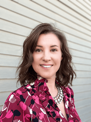 Photo description: Headshot of Kate Valenti, outside, wearing a floral pink shirt