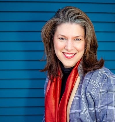 Photo description: Headshot of Ashley Andersen Zantop, outside, in a check blazer and red scarf
